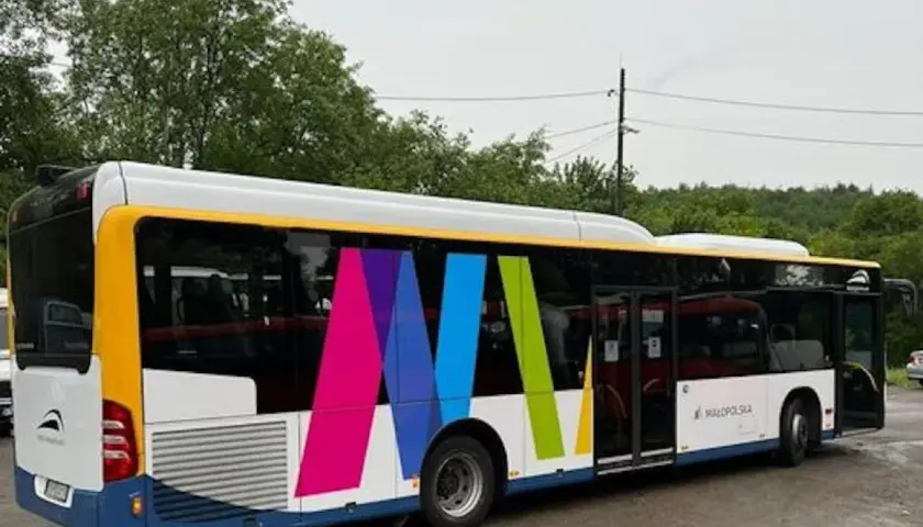 Autobus z kolorowym logo i napisem "Małopolska" na tle drzew.