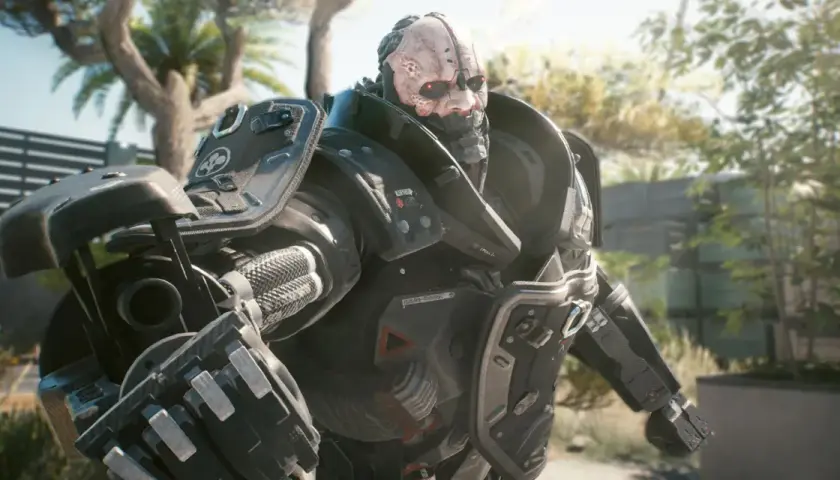 Adam Smasher, potężny cyborg z Cyberpunk 2077, w pełnej zbroi, z czerwonymi oczami i bliznami na twarzy, stoi na tle słonecznego ogrodu.