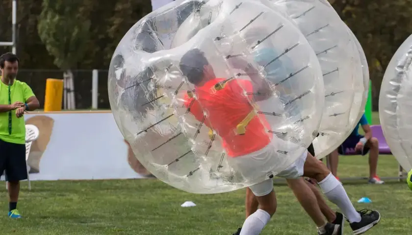 Gracze w wielkich, przezroczystych kulach zderzają się podczas gry w bubble football.
