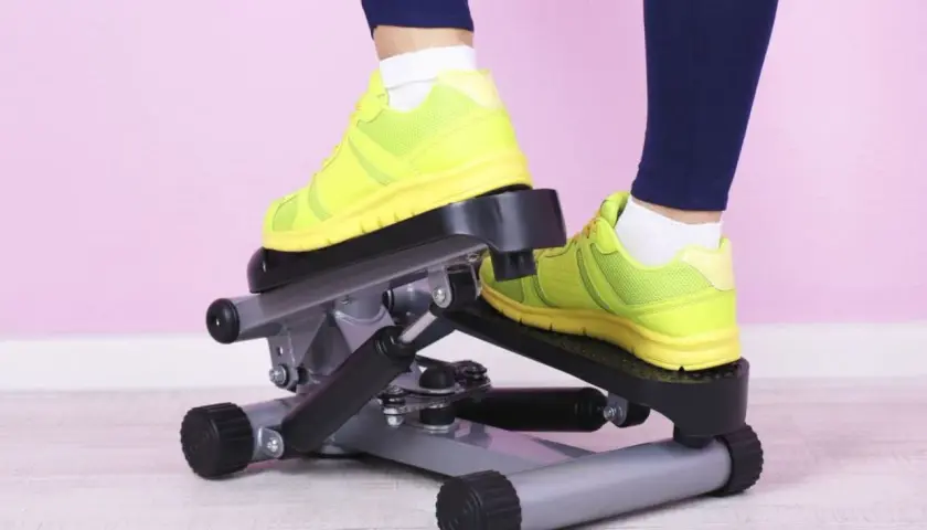 Osoba w neonowych butach ćwiczy na stepperze.