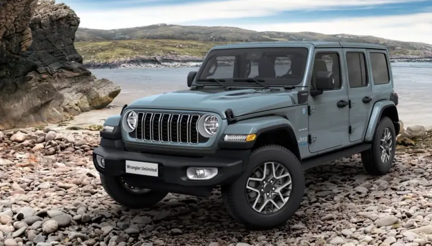 Szary Jeep Wrangler Unlimited na kamienistej plaży. Idealny na przygodę, rozważ jeep leasing.