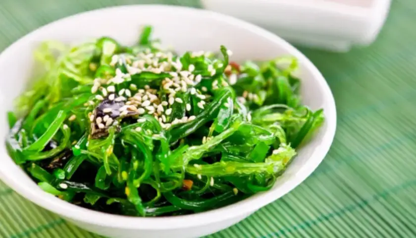 A vibrant green seaweed salad, sprinkled with sesame seeds, perfect for healthy kelp recipes.