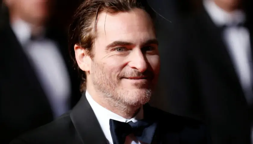Joaquin Phoenix, który grał Jokera w filmie Joker, w czarnym smokingu i muszce.