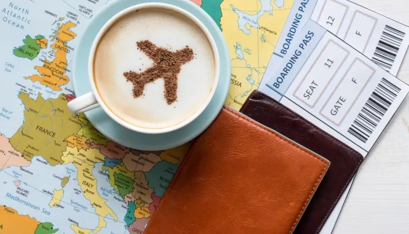 Une tasse de café avec un avion en cacao sur une carte du monde, à côté de billets d'avion. L'idée d'un voyage, d'une carte pass et étape.