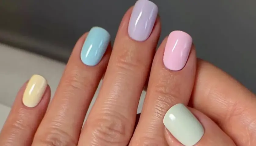Manos con uñas de verano elegantes en tonos pastel: amarillo, azul, lila, rosa y verde menta.