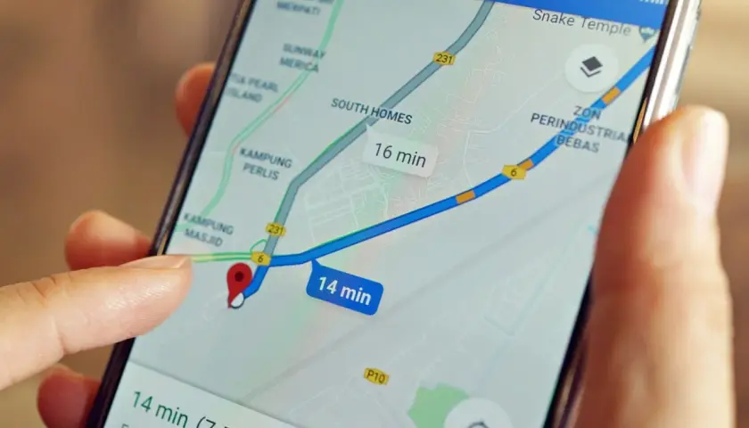Palec wskazuje na mapę na ekranie telefonu, pokazując trasę z szacowanym czasem 14 minut. Możesz łatwo wysłać pinezkę z lokalizacją.