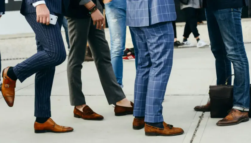 Un groupe d'hommes élégants, leurs pantalons tombant sur leurs chaussures, arborent des styles variés, du costume à rayures aux jeans.