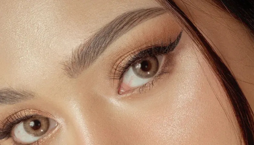 Un maquillage yeux sophistiqué avec un trait d'eye-liner fin et des fards dorés scintillants.