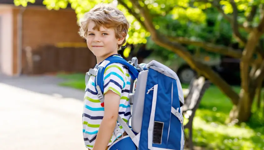 Niño sonriente con mochila azul, listo para ir al cole.