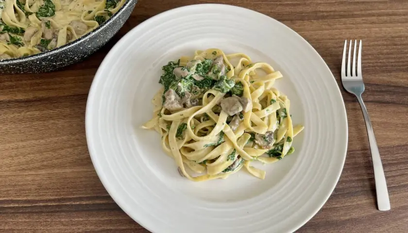 Pyszne fettuccine z kremowym sosem, pieczarkami i szpinakiem. Idealne danie na szybki obiad.