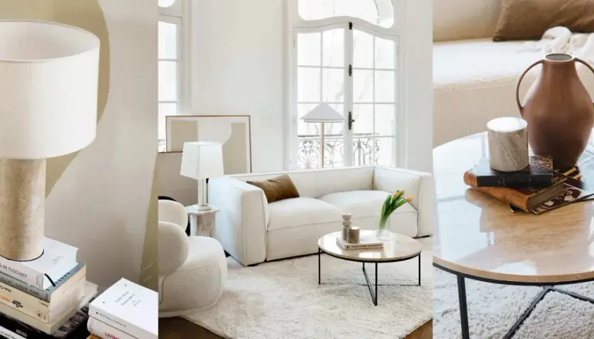 Un salon sans tv, ambiance cosy avec canapé blanc, table basse en marbre et lampes. Des livres et des vases décorent l'espace.