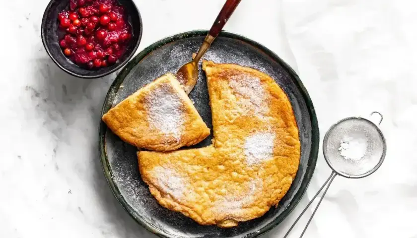 Puszysty omlet z airfryer, posypany cukrem pudrem, podany z żurawiną. Idealny na śniadanie.