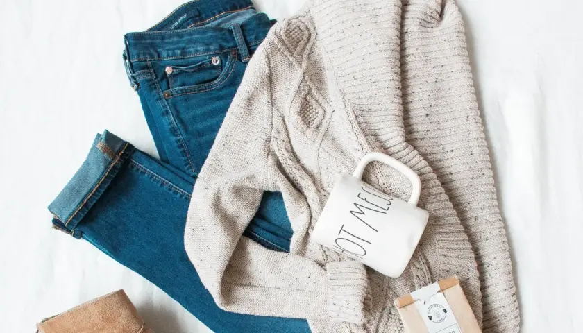 Ensemble pour s'habiller en hiver : jean, pull torsadé, bottines beiges, tasse et sachet de thé.