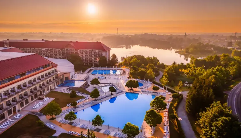 Hotel Gołębiewski Mikołajki o wschodzie słońca. Widok na rozległy kompleks basenów i jezioro.