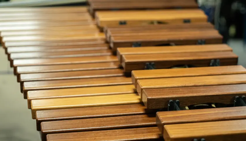 Drewniane klawisze marimby, instrumentu perkusyjnego melodycznego, obok innych instrumentów perkusyjnych niemelodycznych w tle.