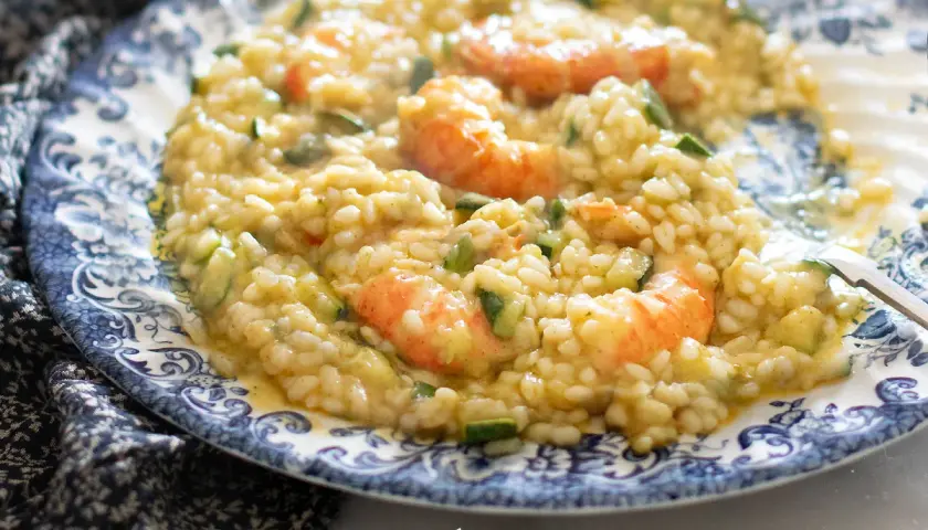 Risotto cremoso con zucchine e gamberetti, un piatto estivo da gustare.