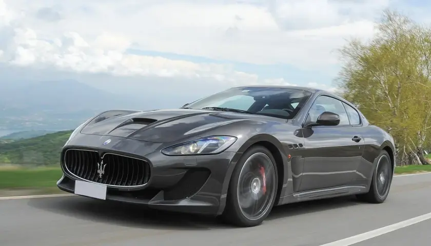 Szary Maserati GranTurismo na krętej drodze. Marzysz o takim aucie? Sprawdź aktualną maserati cena!