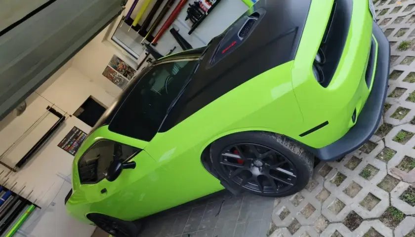 Jasnozielony Dodge Challenger z czarną maską i dachem, gotowy do oklejenia. Zastanawiasz się, ile kosztuje oklejenie auta?