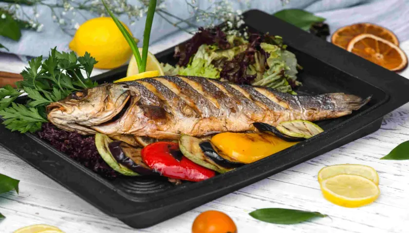Apetyczna ryba z piekarnika z warzywami: grillowany bakłażan, cukinia, papryka, podana z sałatką i cytryną.