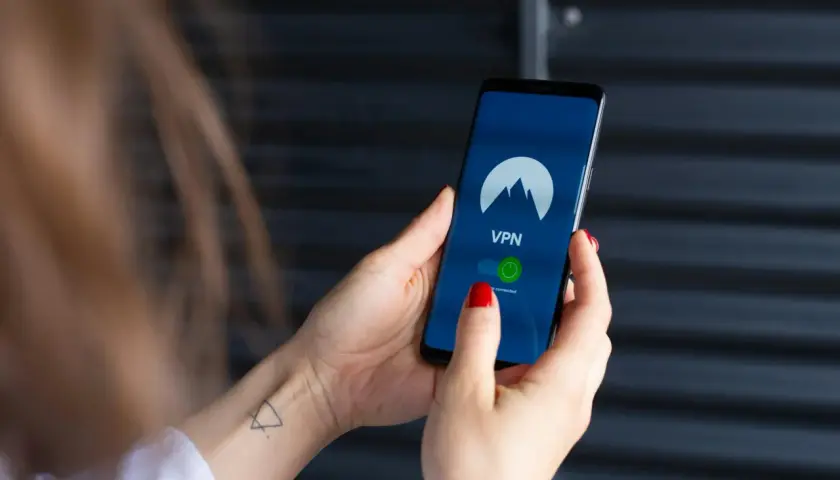 Dłoń trzyma smartfon z włączoną aplikacją VPN, gotową do zabezpieczenia połączenia, jak w najnowszych wersjach android 15.
