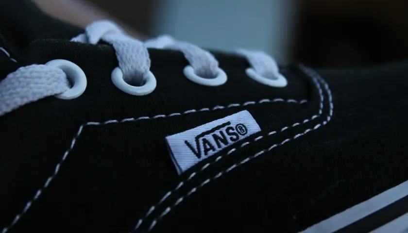 Zbliżenie na czarną tkaninę buta Vans z białymi sznurówkami i charakterystyczną metką.