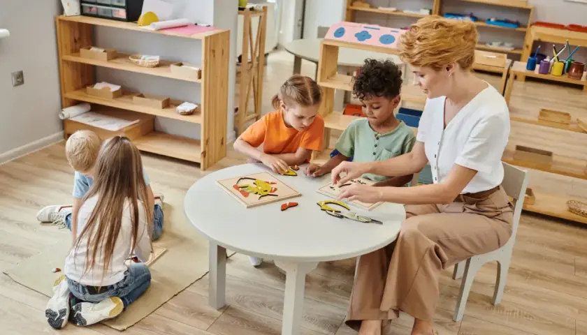 Niños y maestra armando rompecabezas en una mesa. Es normal que los niños se toquen entre ellos mientras aprenden y juegan juntos.