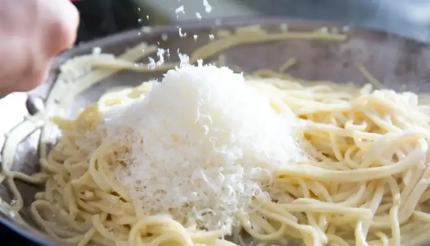 Szukając alternatywy dla parmezanu do pesto, dodaję starty ser do gorącego makaronu w patelni.