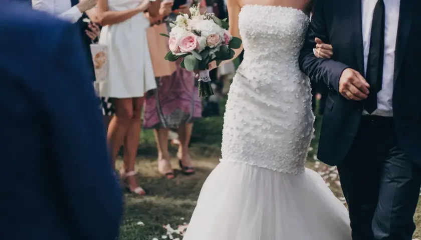 Przepiękna suknia ślubna rybka, niczym syrena, podkreśla sylwetkę panny młodej. Bukiet róż i piwonii dopełnia jej ślubny look.