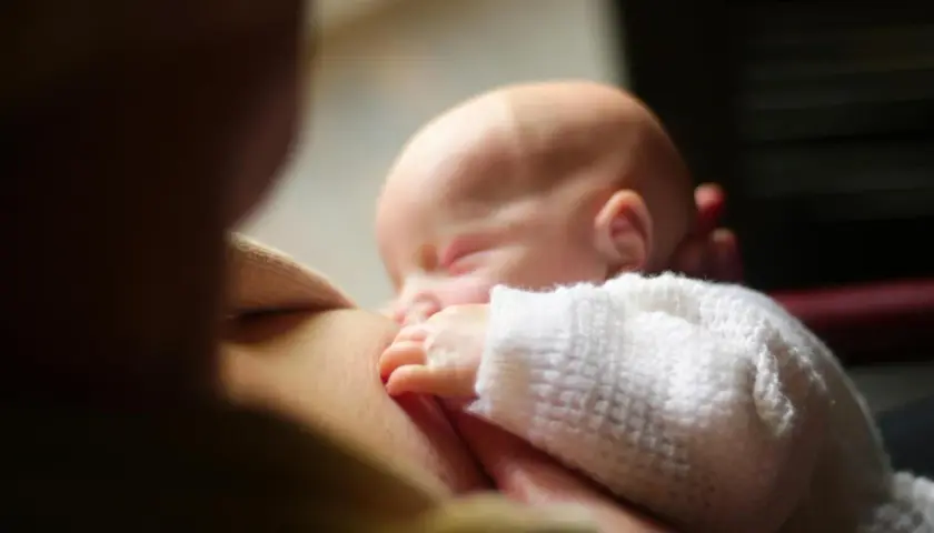Un neonato dorme serenamente mentre viene allattato. Un momento intimo che fa riflettere su cosa mangiare in allattamento per il benessere di entrambi.