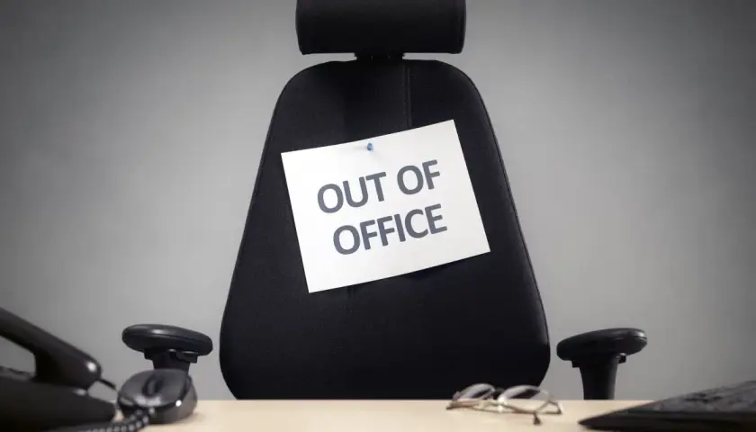 Puste biurowe krzesło z kartką "OUT OF OFFICE". Czas na zasłużone święta w sierpniu!