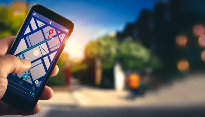 Dłoń trzyma smartfon z mapą i trasą. Dowiedz się, jak włączyć nawigację w telefonie, by łatwo dotrzeć do celu.