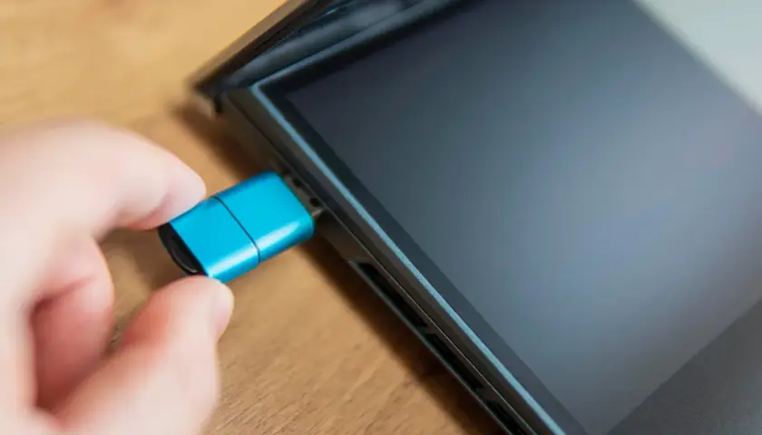 Dłoń podłącza niebieski pendrive do iPada. Dowiedz się, jak podłączyć pendrive do iPada, aby łatwo przenosić pliki.