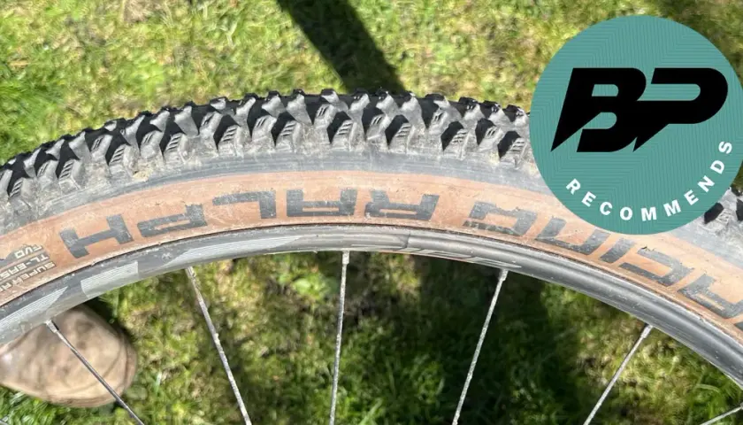 Close-up of a Schwalbe Racing Ralph tire on a bike wheel, ready for a review. The tan sidewall shows the "RALPH" branding.