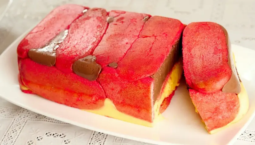 Zuppa inglese ricetta originale emiliana: strati di pan di Spagna rosso e giallo, crema al cioccolato e liquore, decorata con savoiardi.