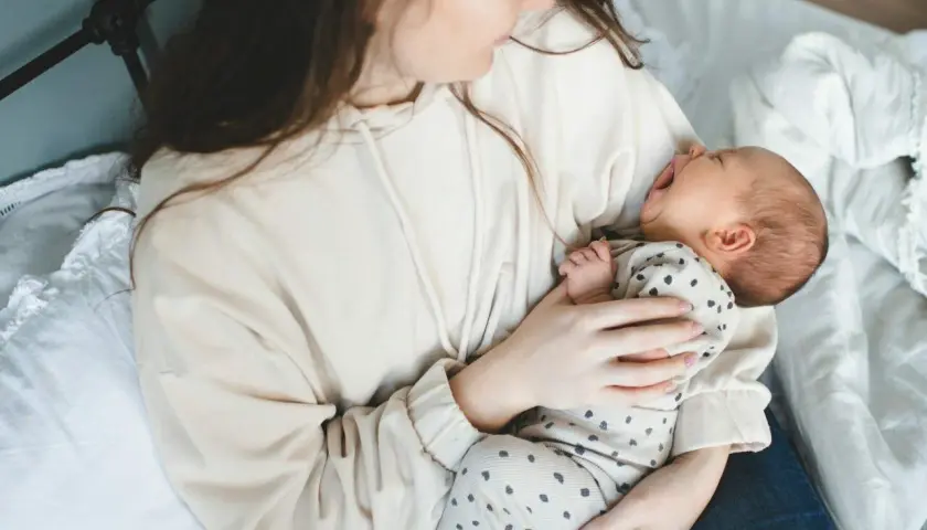 Mama tuli do synka, który właśnie zaczął wymioty u niemowlaka. Dziecko z otwartą buzią, mama tuli go czule.