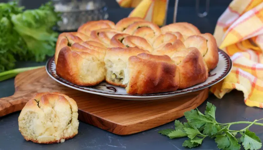 Puszysty chlebek ziołowy z Thermomixa, upieczony na złoto, z zieloną natką pietruszki obok.