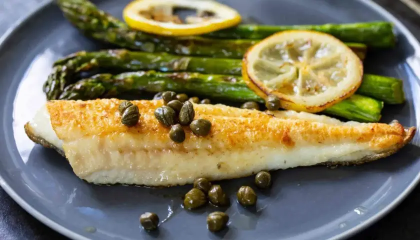 Sogliola in friggitrice ad aria, dorata e succulenta, servita con asparagi croccanti, capperi e fette di limone.