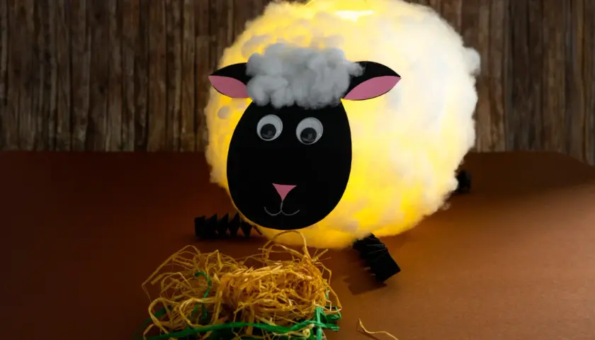 Ein leuchtendes Schaf, gebastelt aus einem Luftballon, mit Watte als Wolle und Papier für Kopf und Ohren.