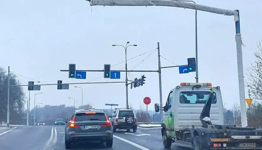 Na skrzyżowaniu widać różne rodzaje kamer monitorujących ruch. Samochody czekają na zielone światło.