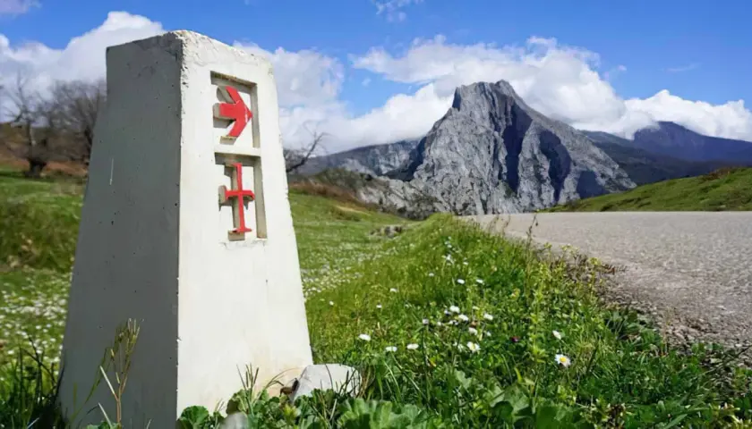 Señal del camino lebaniego, indicando la ruta. El paisaje montañoso sugiere la dificultad del camino.