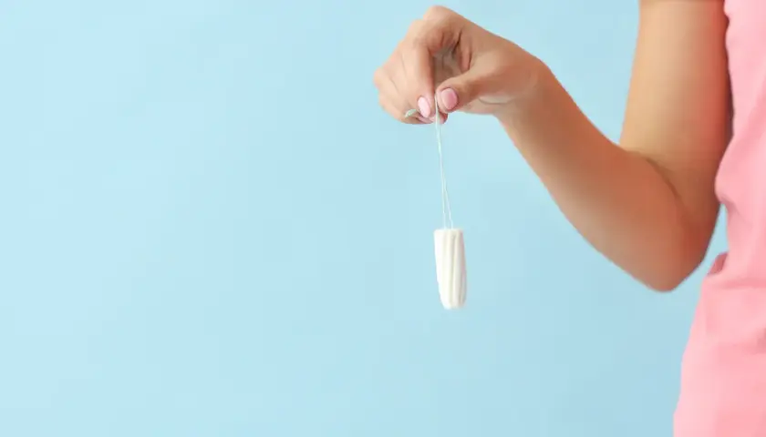 Dłoń trzyma tampon. To produkt higieniczny, który po angielsku nazywa się "tampon".