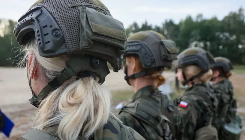 Kobiety w mundurach i hełmach, gotowe do służby. Wiek poborowy w Polsce to ważny temat, a te żołnierki pokazują siłę i determinację.