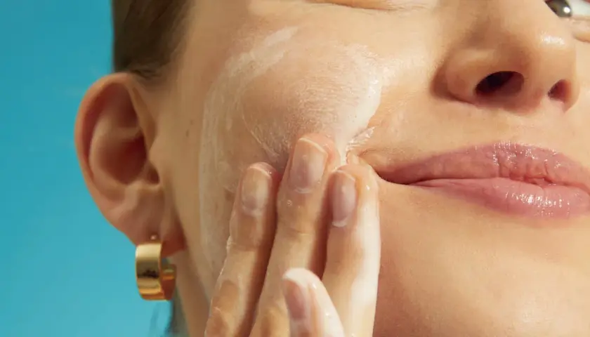 Mani delicate massaggiano schiuma sul viso, cercando sollievo per la pelle irritata.