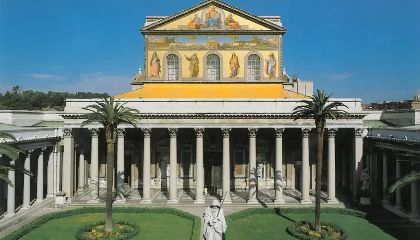 La **cattedrale San Paolo Roma** vista dal cortile con statue, palme e un prato curato.