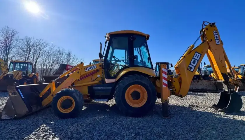 Żółta koparko-ładowarka JCB na placu budowy, gotowa do pracy.