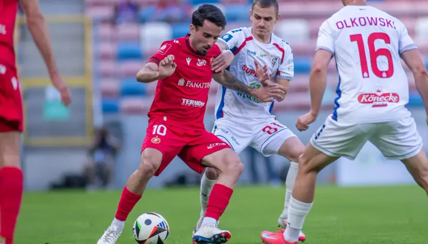 Piłkarze Widzewa Łódź i Górnika Zabrze walczą o piłkę. Czerwona koszulka z numerem 10 i biała z numerem 16.