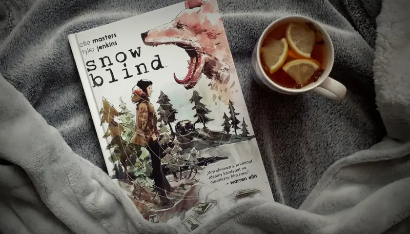 Okładka komiksu "Snow Blind" z wilkiem i postacią w lesie. Obok kubek z herbatą i cytryną. Idealny thriller na zimowe wieczory.