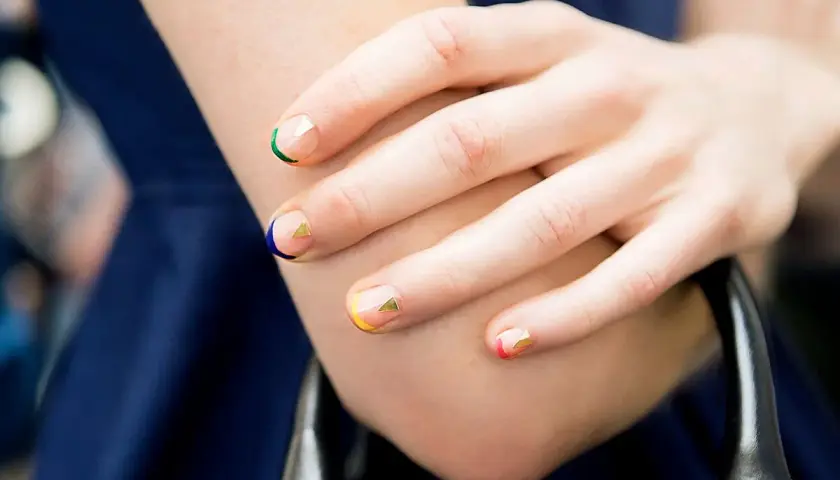 Manicura geométrica con colores vibrantes y detalles dorados en uñas cortas bonitas.