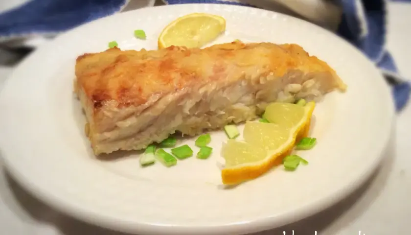 Un filetto di pesce persico cotto in padella, guarnito con spicchi di limone e erba cipollina. Perfetto per una ricetta pesce persico in padella al limone leggera e gustosa.