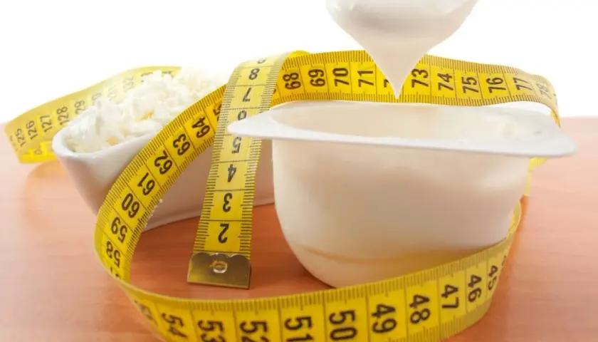 Biały jogurt i twaróg owinięte miarką. Czy od białka się tyje? Zdrowa dieta to klucz do sukcesu.